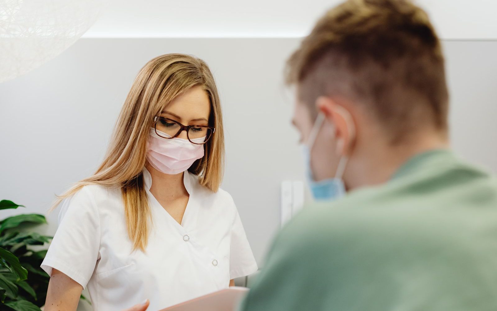 Accueil d'une clinique, une soignante consulte un document avec une personne