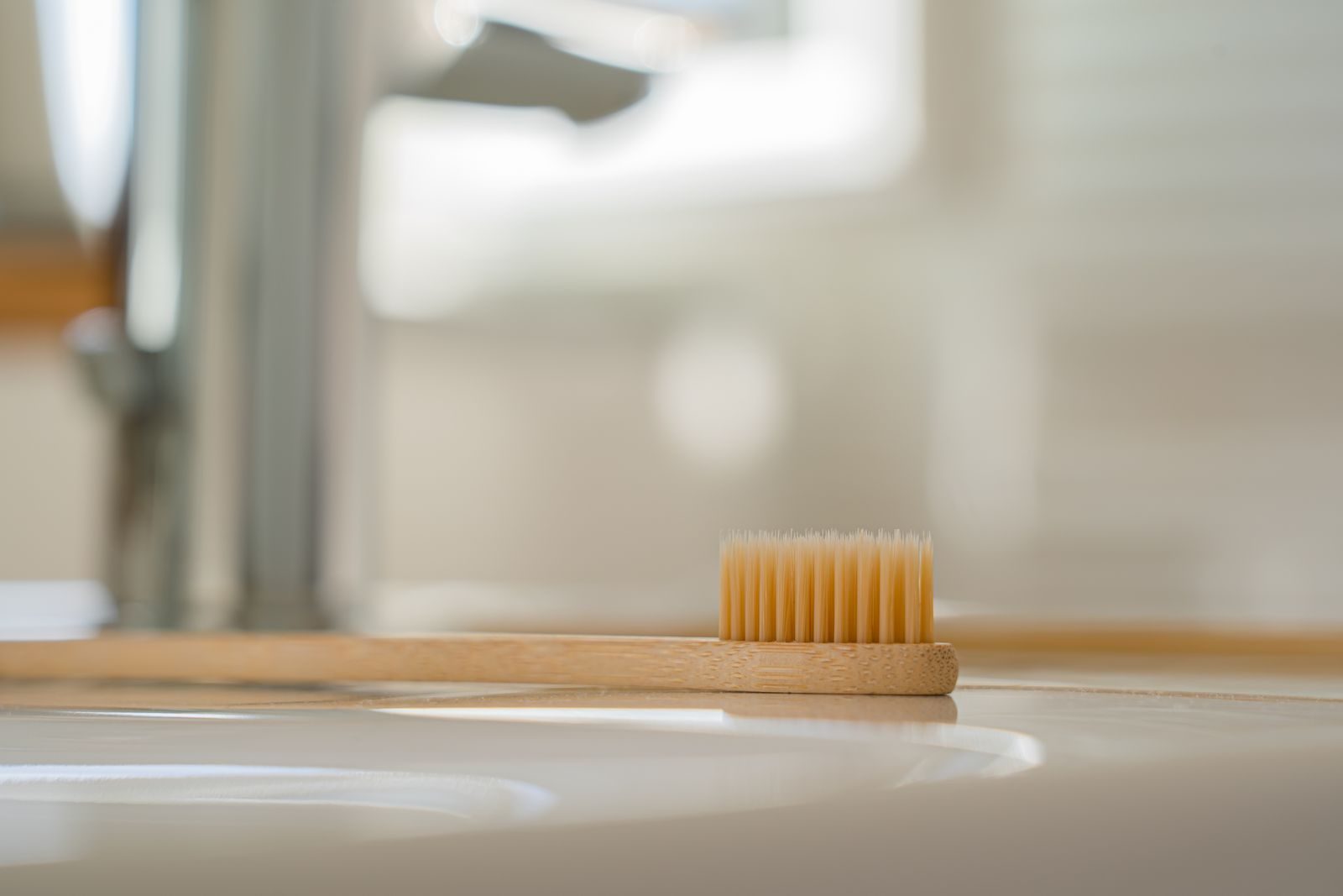 Brosse à dents en bambou posée au bord d'un lavabo